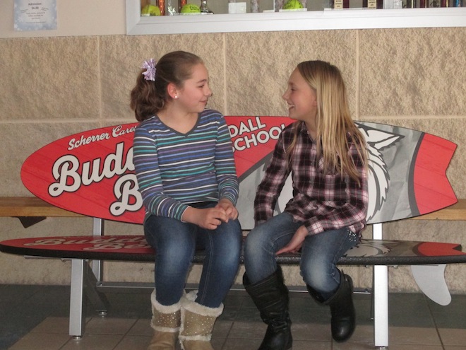 Maddy Pedersen and Allie Anderson, Randall fifth-graders, engage in conversation on the school's new Buddy Bench, donated by Scherrer Cares Buddy Bench Program (Photo by Jason Arndt).